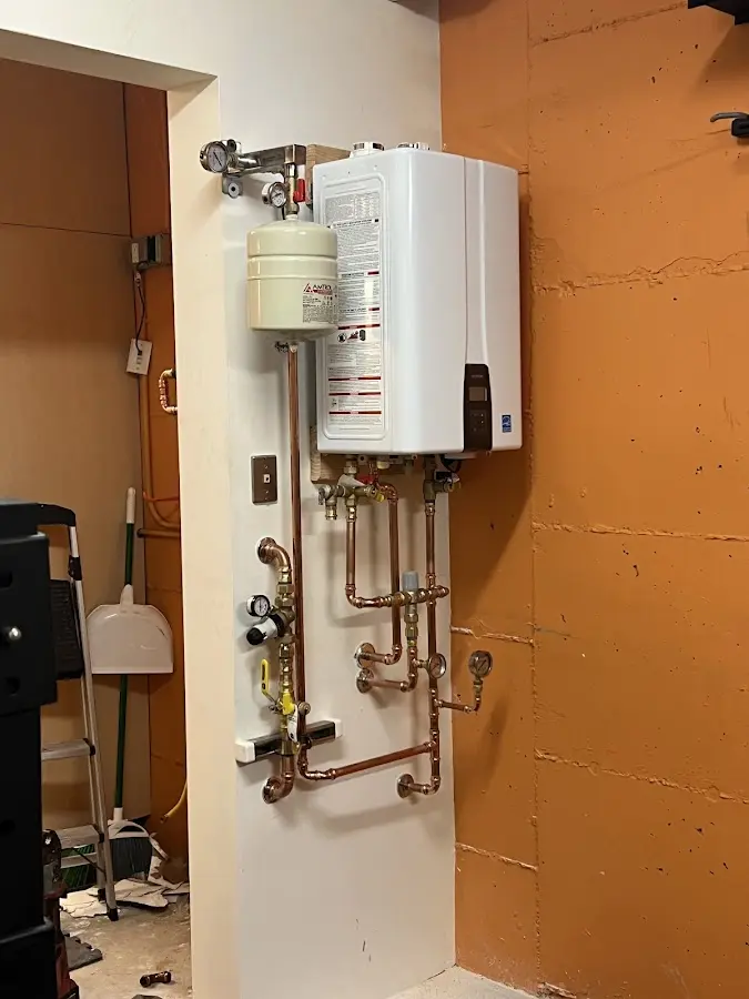 Plumbing technician inspecting water heater connections in Strasburg